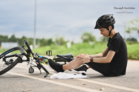 Junge sitzt neben seinem Fahrrad, weil er abgestürzt ist und hält sich das Knie